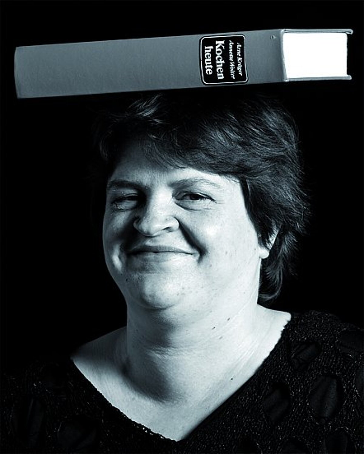 Lächelnde Frau balanciert ein Buch auf dem Kopf