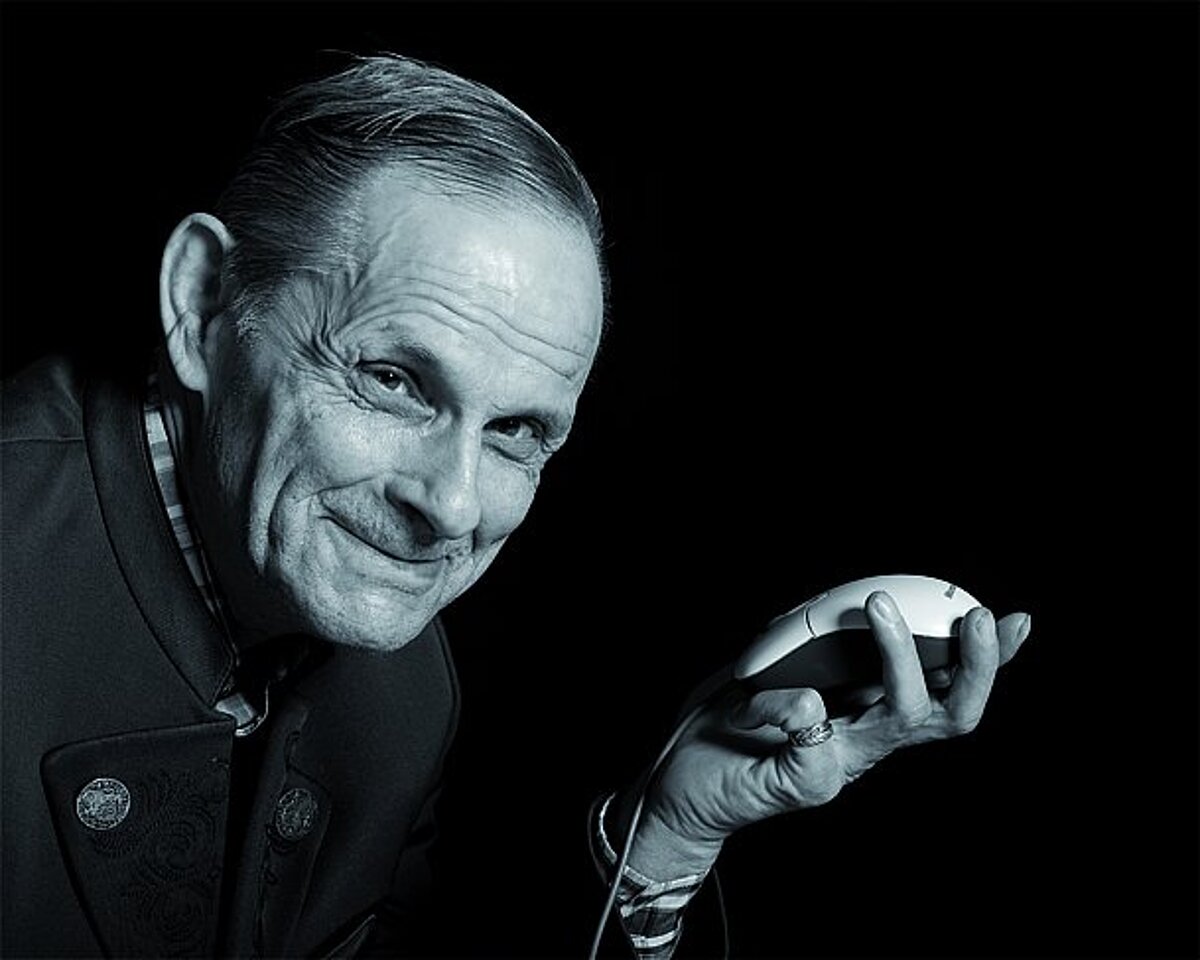 Älterer Herr hält eine Computermaus in der Hand